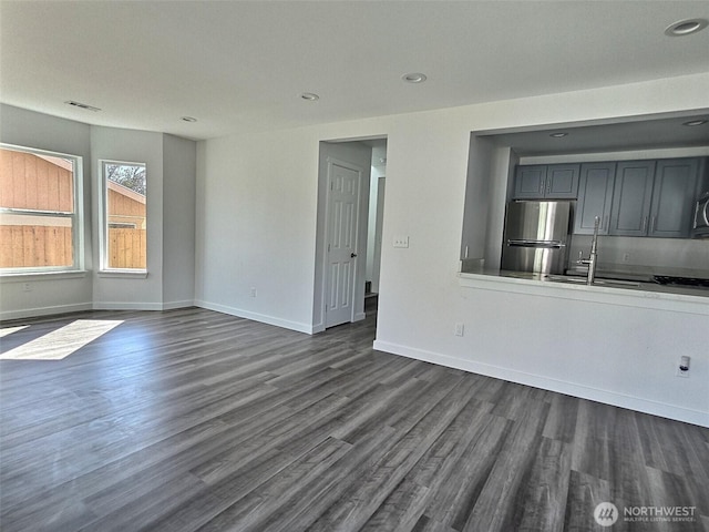 408-410 E 4th St, Warden, WA 98857 - unfurnished living room featuring dark wood-style flooring, baseboards, recessed lighting, and a sink