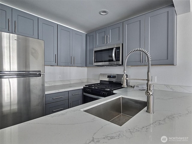 408-410 E 4th St, Warden, WA 98857 - kitchen featuring appliances with stainless steel finishes, light stone counters, gray cabinetry, a sink, and recessed lighting
