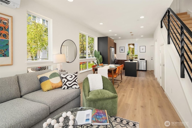 living room featuring light wood-style floors, recessed lighting, and a wall unit AC