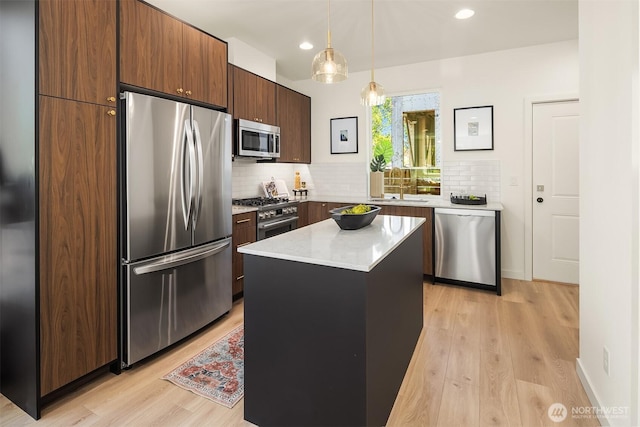kitchen with appliances with stainless steel finishes, a sink, light wood finished floors, backsplash, and recessed lighting