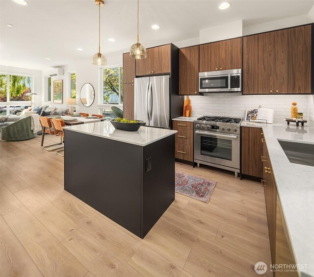 kitchen featuring appliances with stainless steel finishes, light wood-style flooring, light countertops, tasteful backsplash, and recessed lighting