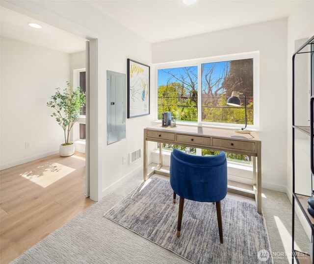 office featuring wood finished floors, baseboards, and electric panel