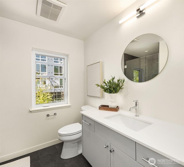 bathroom featuring tile patterned floors, toilet, vanity, baseboards, and a shower