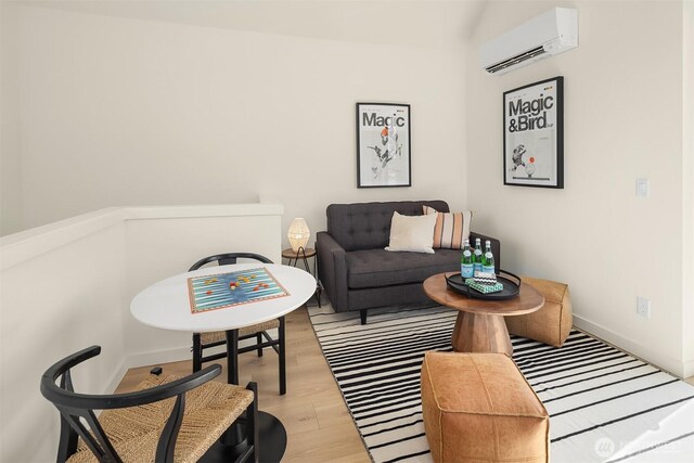 living area with a wall mounted AC, wood finished floors, and baseboards
