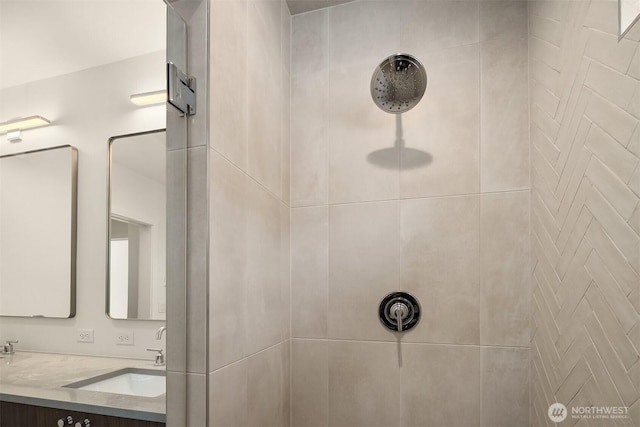 full bath with tiled shower and double vanity
