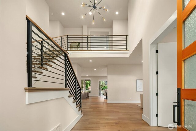 entrance foyer with wood finished floors, a chandelier, a high ceiling, stairway, and recessed lighting