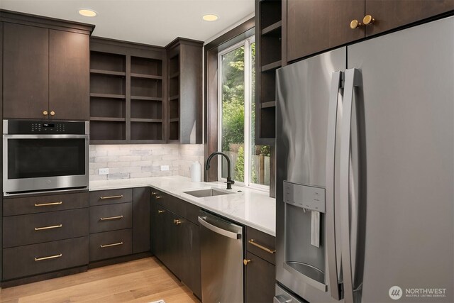kitchen featuring stainless steel appliances, open shelves, a sink, dark brown cabinets, and recessed lighting