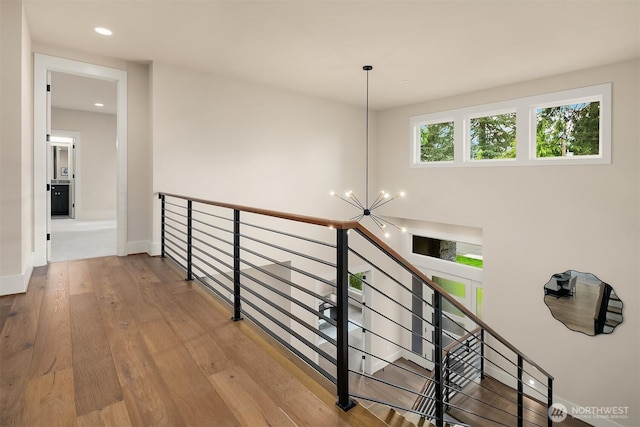 hall with an upstairs landing, a chandelier, wood finished floors, baseboards, and recessed lighting