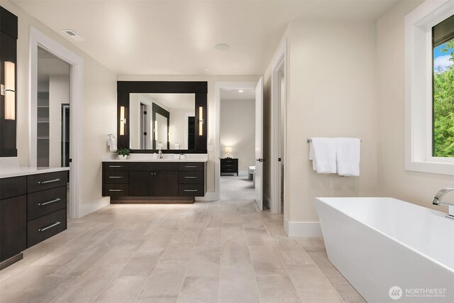 full bathroom with a freestanding bath, vanity, toilet, recessed lighting, and baseboards