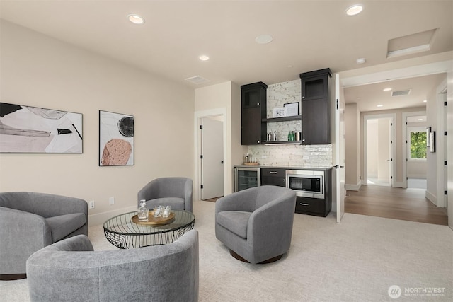living area featuring bar area, wine cooler, recessed lighting, and light carpet