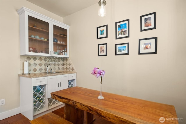 indoor wet bar with backsplash, wood finished floors, and baseboards