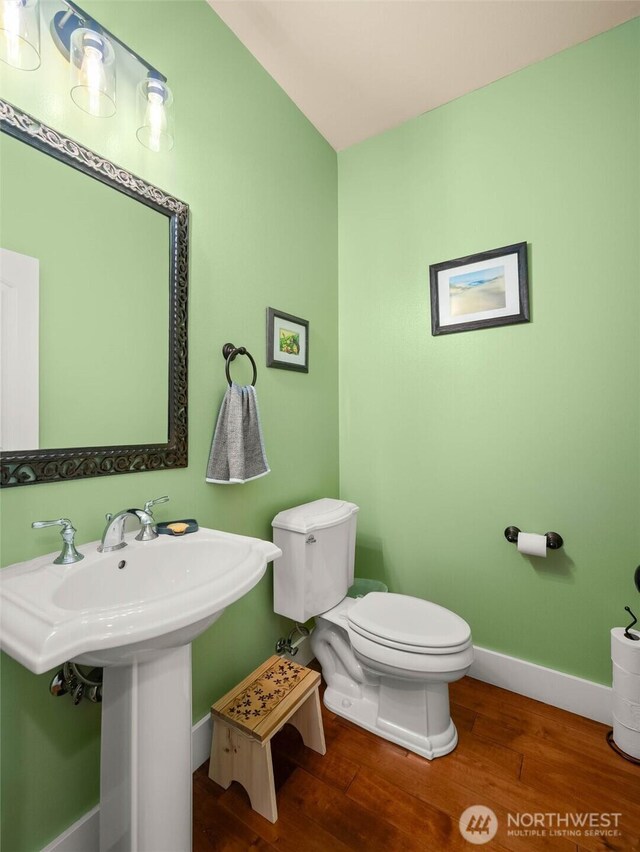 bathroom featuring baseboards, wood finished floors, and toilet