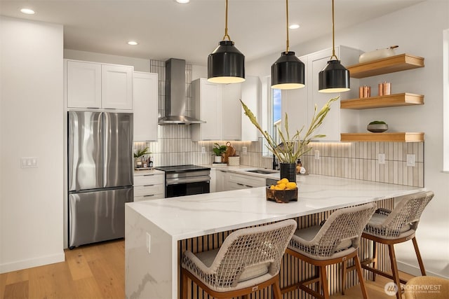 kitchen featuring stainless steel appliances, wall chimney exhaust hood, a peninsula, backsplash, and light stone countertops