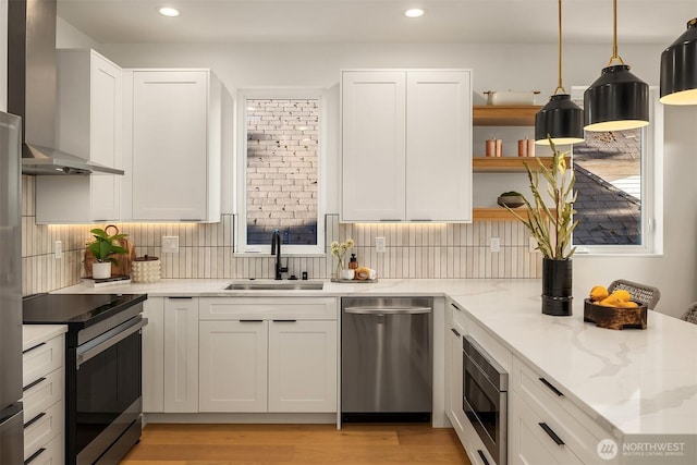 kitchen with appliances with stainless steel finishes, a sink, wall chimney exhaust hood, recessed lighting, and tasteful backsplash