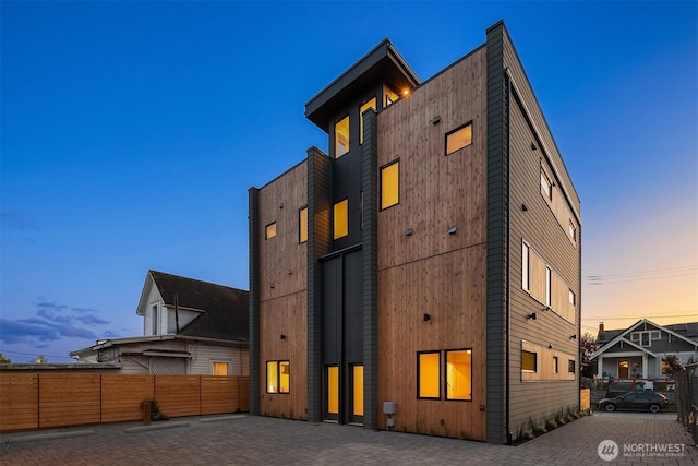 back of house at dusk featuring fence