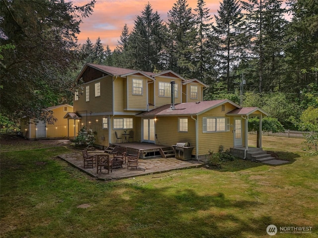 back of property at dusk with a patio area and view of wooded area
