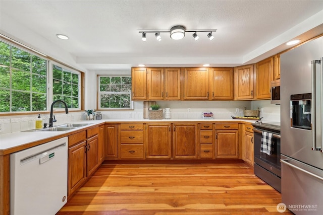kitchen with stainless steel appliances, a sink, brown cabinets, and recessed lighting