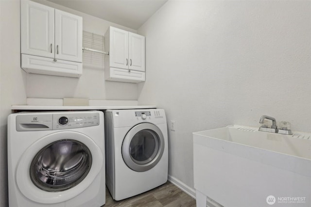 laundry area with cabinet space, washer and clothes dryer, wood finished floors, and baseboards