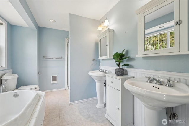 bathroom featuring a bath, toilet, a sink, a shower stall, and heating unit