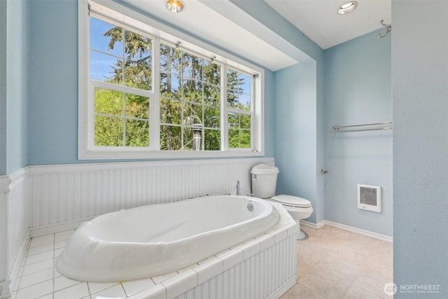 full bath featuring toilet, a bath, heating unit, and tile patterned floors