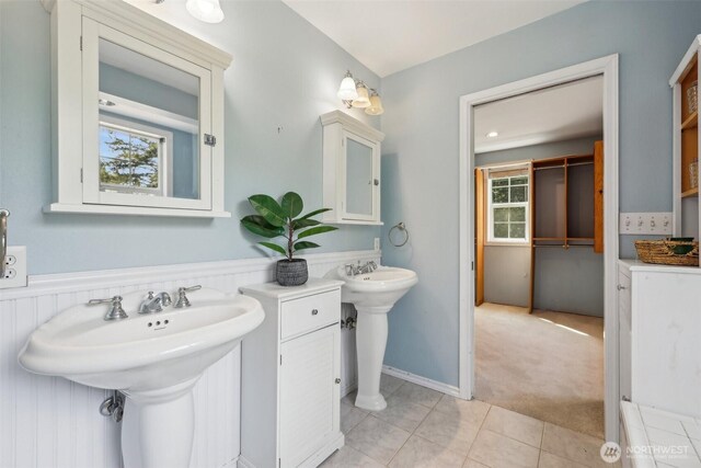 bathroom featuring tile patterned floors, wainscoting, and two sinks