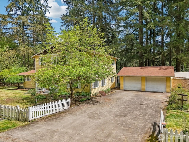 view of front of house featuring an outbuilding, a detached garage, and fence