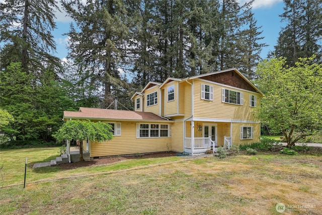 view of front facade featuring a front lawn, a porch, french doors, and view of wooded area