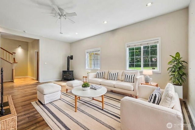 living area featuring wood finished floors, a ceiling fan, a wood stove, recessed lighting, and baseboards