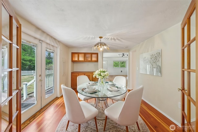 dining area with french doors, light wood-style flooring, and baseboards