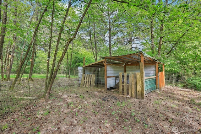 view of poultry coop featuring fence and a forest view