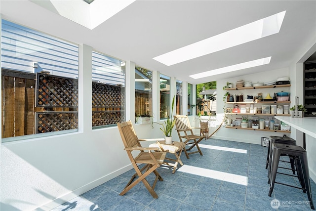 sunroom / solarium with a skylight, tile patterned floors, and baseboards