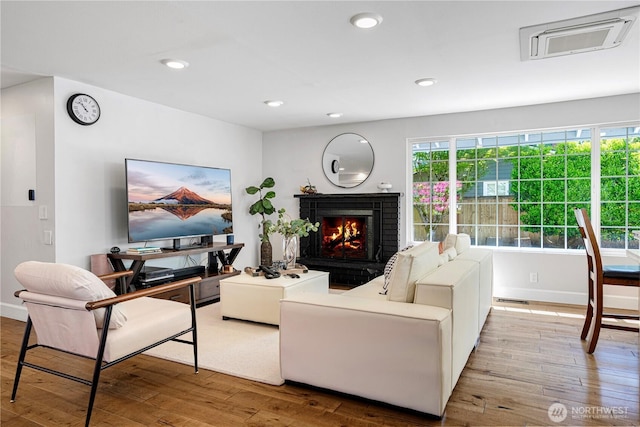 living area featuring hardwood / wood-style flooring, a brick fireplace, baseboards, and recessed lighting