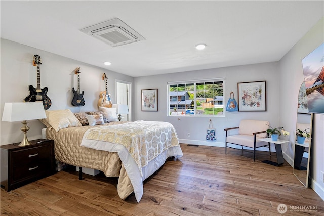 bedroom with wood finished floors, baseboards, and recessed lighting