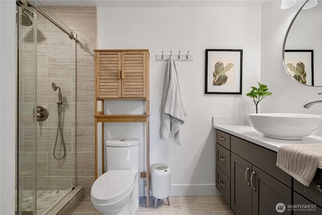 full bathroom featuring baseboards, a stall shower, vanity, toilet, and wood finished floors