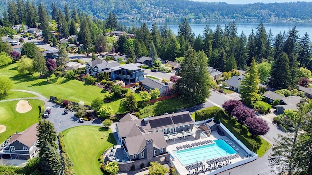 aerial view of residential area featuring a large body of water, a local golf course, a pool area, and a forest