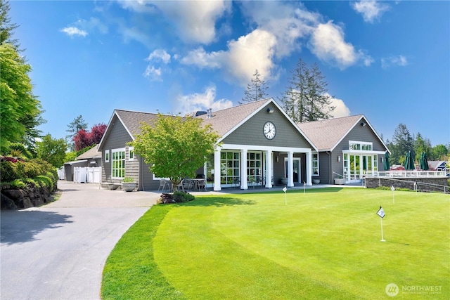 back of property with a putting green, fence, and roof with shingles