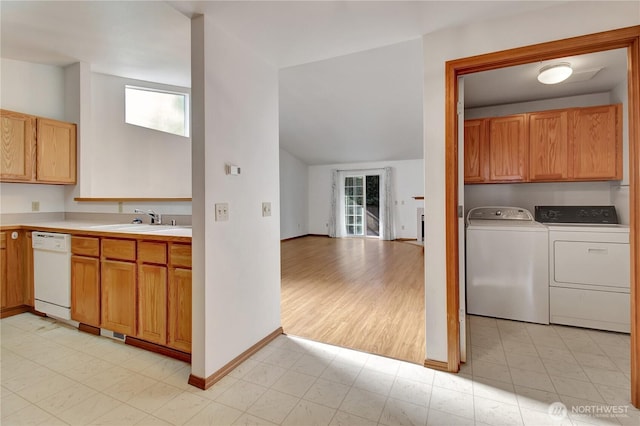 kitchen featuring dishwasher, a sink, separate washer and dryer, light countertops, and baseboards