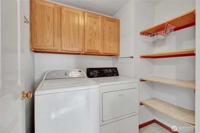 clothes washing area featuring washer and clothes dryer, cabinet space, and baseboards