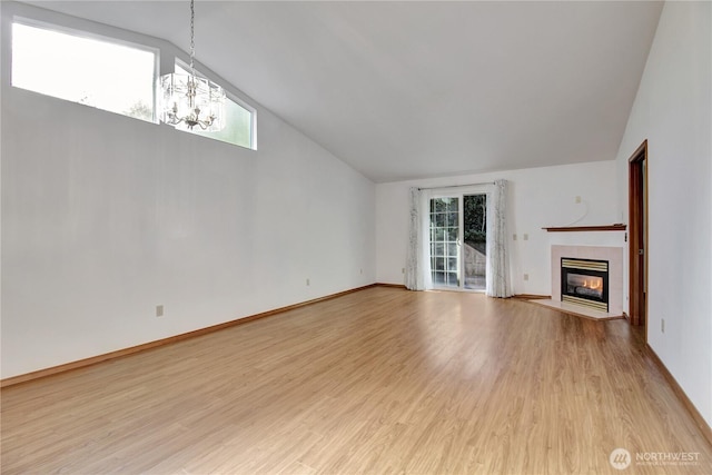unfurnished living room featuring a chandelier, plenty of natural light, a fireplace, light wood-style floors, and high vaulted ceiling