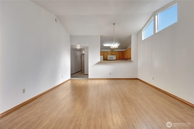 unfurnished living room with lofted ceiling, light wood-style flooring, and baseboards
