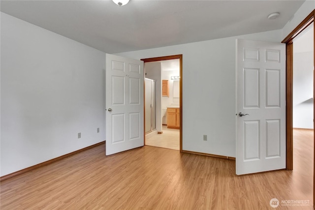 unfurnished bedroom featuring light wood-type flooring, baseboards, and ensuite bath