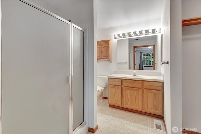 bathroom featuring tile patterned floors, a shower stall, toilet, and vanity