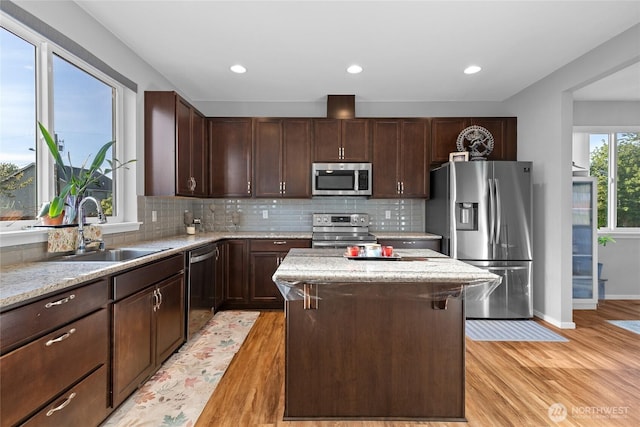 11511 SE 244th, Kent, WA 98030 - kitchen with appliances with stainless steel finishes, a sink, a center island, light wood finished floors, and backsplash