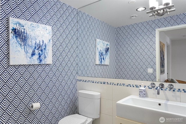 8631 NE 19th Pl, Clyde Hill, WA 98004 - bathroom with a sink, toilet, tile walls, a chandelier, and wallpapered walls