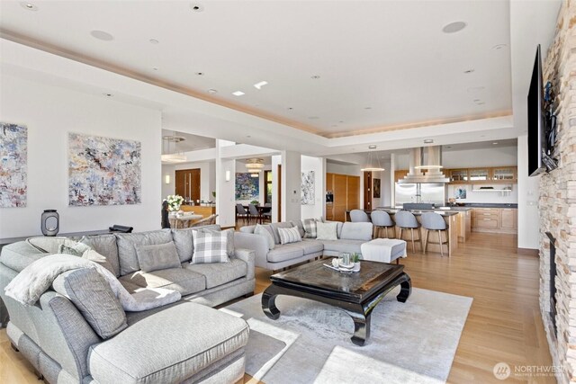 8631 NE 19th Pl, Clyde Hill, WA 98004 - living room with a tray ceiling, light wood-type flooring, and a stone fireplace