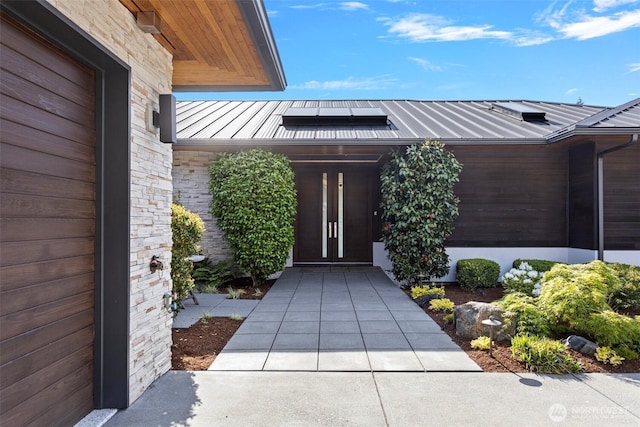 8631 NE 19th Pl, Clyde Hill, WA 98004 - doorway to property with a standing seam roof, metal roof, stone siding, and roof mounted solar panels