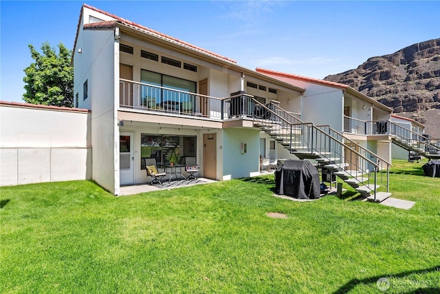 back of house with stairway, a yard, stucco siding, and a mountain view