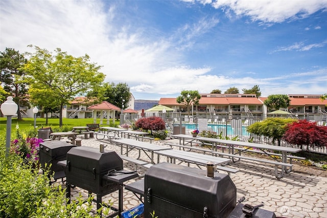 view of community with fence, a swimming pool, and a patio area