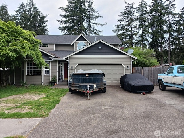 traditional-style house featuring an attached garage, driveway, fence, and a shingled roof