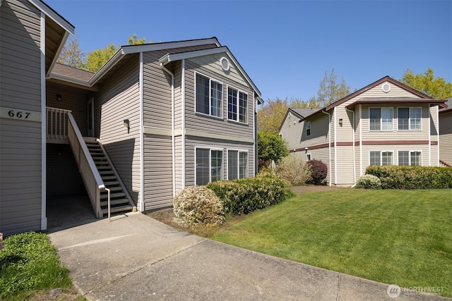 view of side of property with stairs and a lawn